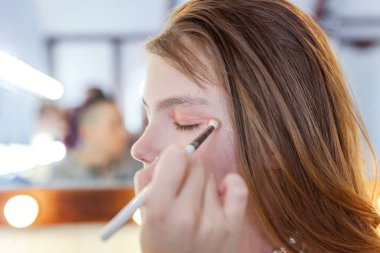 Makyaj ana uygulanan göz farı küçük güzel kız modeli için el. Profesyonel olun sanatçı tarafından uygulanıyor. Kalıcı makyaj ayrıntılı işlem olarak. Tarzı çocuk güzellik salonu photosession kavramı