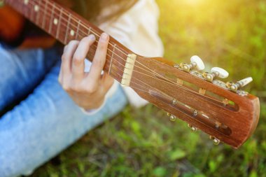 Kadın closeup park veya bahçe arka plan üzerinde akustik gitar çalmak eller. Genç kız şarkı ve yazma müzik oynamak için öğrenme. Hobi, lifestyle, sakin ol, enstrüman, eğlence, eğitim kavramı