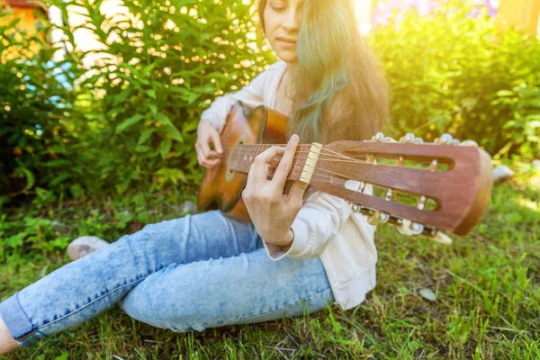 年轻的嬉皮士妇女坐在草地上 在公园或花园的背景下弹吉他 十几岁的女孩学习播放歌曲和写音乐 生活方式 教育理念 — 图库照片