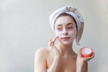 Bir havlu yüz izole beyaz arka plan üzerinde beyaz besleyici maske veya krem uygulayarak kafasına gülümseyen bir esmer kadın güzellik portresi. Cilt Bakımı temizlik spa kavramı relax