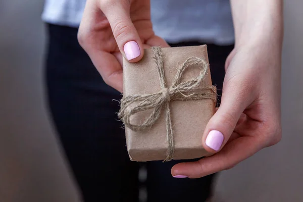 女性手拿着小礼品盒包裹工艺纸与丝带 小圣诞节或新年装饰礼物在女人的手中 圣诞节生日情人节庆祝礼物浪漫的概念 — 图库照片