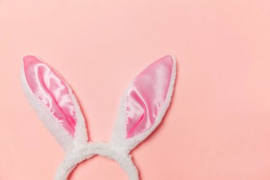 Mutlu Paskalya kavramı. Tatil için hazırlık. Dekoratif tavşan kulakları kürklü kabarık kostüm oyuncak trendy pastel pembe arka plan üzerinde izole. Üstten görünüm kopya alanı basit minimalizm düz yatıyordu