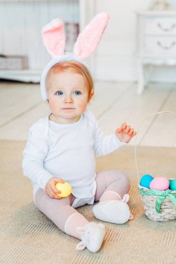 Küçük çocuk kız tavşan kulakları Paskalya gününde giyiyor. Paskalya yumurtası avına eğleniyor evde, katta oturan boyalı yumurta ile sepeti tutan kız. Mutlu Paskalya tatil kutlama bahar kavramı