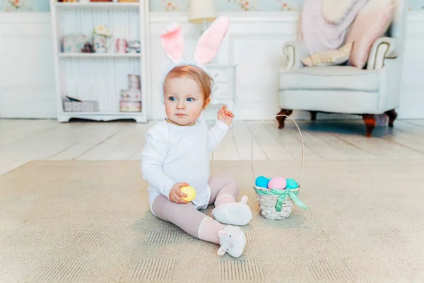 Petite fille enfant portant des oreilles de lapin le jour de Pâques et jouant avec des œufs peints — Photo
