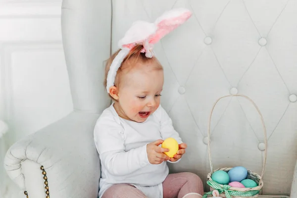 Lilla barnflickan bär bunny öron på påskdagen och leker med målade ägg — Stockfoto