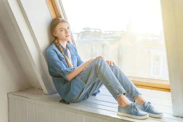 Flickan sitter på ett fönster — Stockfoto