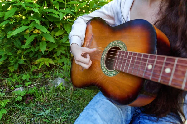 特写镜头的妇女手演奏声学吉他在公园或花园背景 十几岁的女孩学习播放歌曲和写音乐 生活方式 教育理念 — 图库照片
