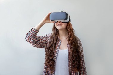 Beyaz arka planda sanal gerçeklik gözlüğü başlığı takan genç kadın gülümse. Sanal gerçeklik gözlüğü takan akıllı telefon. Teknoloji, simülasyon, yüksek teknoloji, video oyunu konsepti