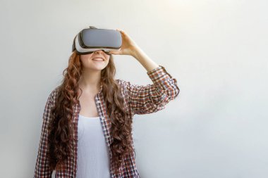 Beyaz arka planda sanal gerçeklik gözlüğü başlığı takan genç kadın gülümse. Sanal gerçeklik gözlüğü takan akıllı telefon. Teknoloji, simülasyon, yüksek teknoloji, video oyunu konsepti