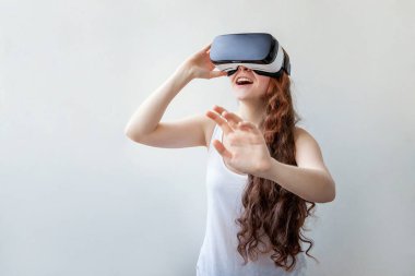 Beyaz arka planda sanal gerçeklik gözlüğü başlığı takan genç kadın gülümse. Sanal gerçeklik gözlüğü takan akıllı telefon. Teknoloji, simülasyon, yüksek teknoloji, video oyunu konsepti