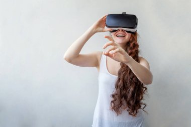 Beyaz arka planda sanal gerçeklik gözlüğü başlığı takan genç kadın gülümse. Sanal gerçeklik gözlüğü takan akıllı telefon. Teknoloji, simülasyon, yüksek teknoloji, video oyunu konsepti