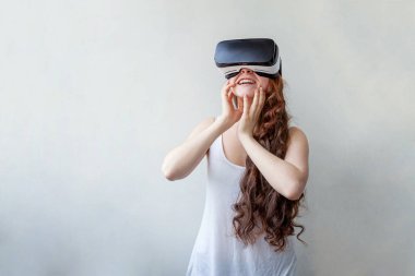 Beyaz arka planda sanal gerçeklik gözlüğü başlığı takan genç kadın gülümse. Sanal gerçeklik gözlüğü takan akıllı telefon. Teknoloji, simülasyon, yüksek teknoloji, video oyunu konsepti