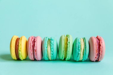 Tatlı badem rengi pembe mavi sarı badem kurabiyesi ya da modayı takip eden mavi pastada izole edilmiş badem kurabiyesi. Fransız kurabiyesi. Asgari gıda fırını konsepti. Düz görünüm kopyalama alanı