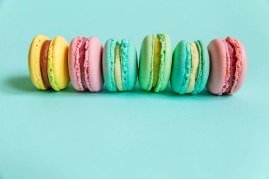 Tatlı badem rengi pembe mavi sarı badem kurabiyesi ya da modayı takip eden mavi pastada izole edilmiş badem kurabiyesi. Fransız kurabiyesi. Asgari gıda fırını konsepti. Düz görünüm kopyalama alanı