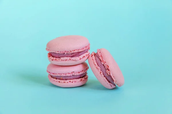 Sweet almond colorful unicorn pink macaron or macaroon dessert cake isolated on trendy blue pastel background. French sweet cookie. Minimal food bakery concept. Copy space