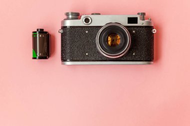 Teknoloji geliştirme hipster fotoğrafçı hobi klasik bellek gezi konsepti. Vintage film fotoğraf kamera lensi ve pembe pastel trendy modern moda pin-up arka plan üzerinde film rulo