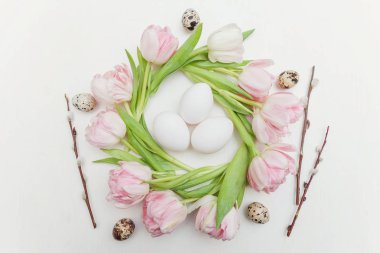 Bahar tebrik kartı. Paskalya yumurta yuva ve pembe taze Lale çiçek buketi beyaz rustik ahşap zemin üzerinde. Paskalya kavramı. Düz yatıyordu üstten görünüm kopya alanı. Bahar çiçekler