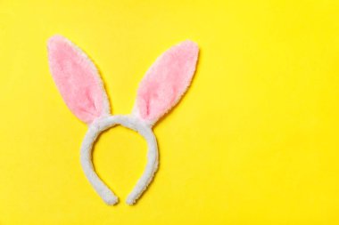Mutlu Paskalya kavramı. Tatil için hazırlık. Dekoratif tavşan kulakları kürklü kabarık kostüm oyuncak trendy sarı arka plan üzerinde izole. Üstten görünüm kopya alanı basit minimalizm düz yatıyordu