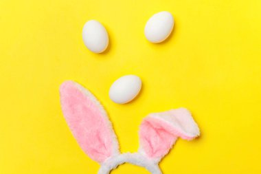 Mutlu Paskalya kavramı. Tatil için hazırlık. Dekoratif beyaz yumurta ve tüylü kostüm oyuncak trendy sarı arka plan üzerinde izole bunny kulaklar. Üstten görünüm kopya alanı basit minimalizm düz yatıyordu
