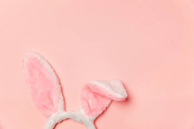 Mutlu Paskalya kavramı. Tatil için hazırlık. Dekoratif tavşan kulakları kürklü kabarık kostüm oyuncak trendy pastel pembe arka plan üzerinde izole. Üstten görünüm kopya alanı basit minimalizm düz yatıyordu