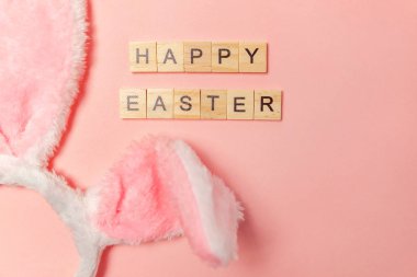Mutlu Paskalya kavramı. Tatil için hazırlık. Yazıt Happy Easter izole trendy pastel pembe arka plan üzerinde dekoratif tavşan kulakları mektuplar. Üstten görünüm kopya alanı basit minimalizm düz yatıyordu