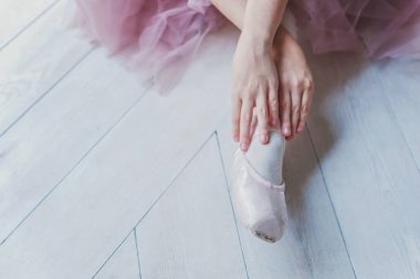 Pembe etekli balerin elleri beyaz ışıklı salonda sivri uçlu ayakkabılar giyer. Dans sınıfındaki genç klasik balerin kız.