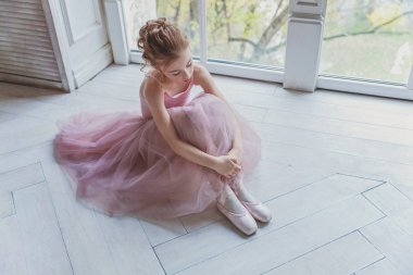 Genç klasik bale dansçı kız dans dersi. Pembe tutu etek beyaz ışık salonunda güzel zarif balerin pratik bale pozisyonlar