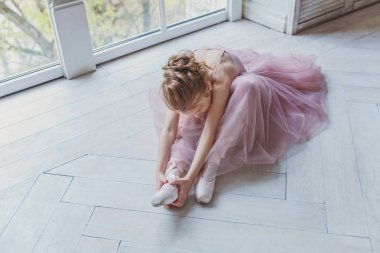 Genç klasik bale dansçı kız dans dersi. Pembe tutu etek beyaz ışık salonunda güzel zarif balerin pratik bale pozisyonlar