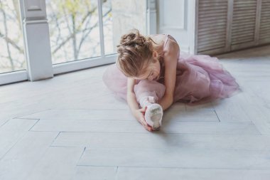 Genç klasik bale dansçı kız dans dersi. Pembe tutu etek beyaz ışık salonunda güzel zarif balerin pratik bale pozisyonlar