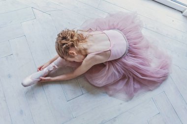 Genç klasik bale dansçı kız dans dersi. Pembe tutu etek beyaz ışık salonunda güzel zarif balerin pratik bale pozisyonlar