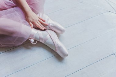 Pembe etekli balerin elleri beyaz ışıklı salonda sivri uçlu ayakkabılar giyer. Dans sınıfındaki genç klasik balerin kız.