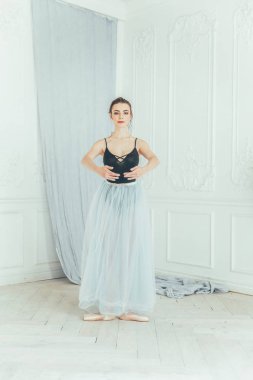 Genç Klasik Bale dansçısı kadın dans dersi. Güzel zarif balerin pratik bale pozisyonlar yakınındaki beyaz ışık salonda büyük ayna mavi tutu etekle