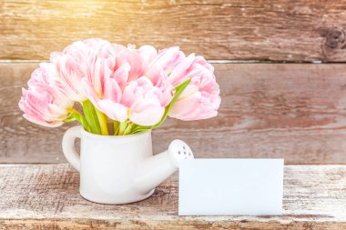 Bahar tebrik kartı. Taze hafif pastel pembe Lale buketi küçük oyuncak sulama olabilir vazo rustik ahşap arka plan üzerinde çiçekler. Mutlu tatil anne gün Sevgililer günü kavramı. Düz yatıyordu üstten görünüm kopya alanı