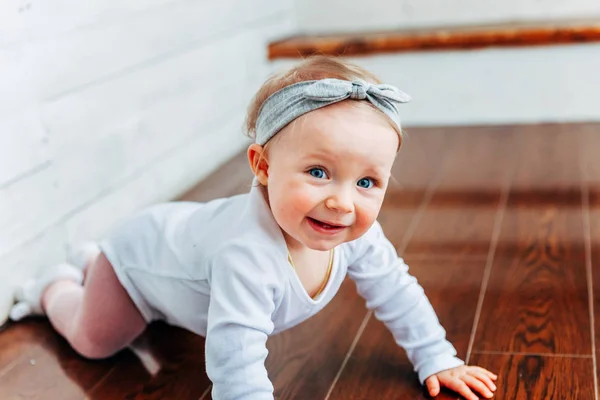 少しクロール赤ちゃん女の子 歳窓際微笑し 笑う明るい光のリビング ルームの床の上します 幸せな幼児の子供が自宅で再生します 小児コンセプト — ストック写真