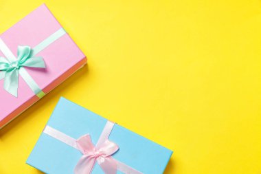 Christmas New Year birthday valentine celebration present romantic concept. Gift box wrapped blue pink paper isolated on yellow colourful trendy modern fashion background. Flat lay top view copy space clipart