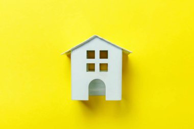 Sade bir şekilde izole sarı renkli şık modern moda arka plan üzerinde beyaz minyatür oyuncak ev tasarım. Mortgage Emlak Sigorta rüya ev concept. Düz yatıyordu üstten görünüm kopya alanı