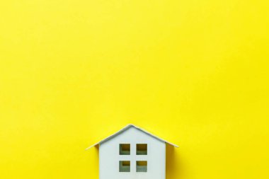 Sade bir şekilde izole sarı renkli şık modern moda arka plan üzerinde beyaz minyatür oyuncak ev tasarım. Mortgage Emlak Sigorta rüya ev concept. Düz yatıyordu üstten görünüm kopya alanı
