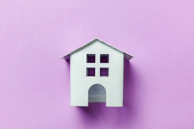 Sadece mor Menekşe pastel renkli şık arka plan üzerinde izole minyatür beyaz oyuncak ev tasarım. Mortgage Emlak Sigorta rüya ev concept. Düz yatıyordu üstten görünüm kopya alanı