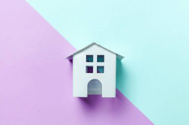 Sadece tasarım mavi mor pastel renkli trendy geometrik arka plan üzerinde izole bir minyatür beyaz oyuncak ev. Mortgage Emlak Sigorta rüya ev concept. Düz yatıyordu üstten görünüm kopya alanı