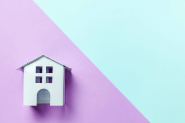 Sadece tasarım mavi mor pastel renkli trendy geometrik arka plan üzerinde izole bir minyatür beyaz oyuncak ev. Mortgage Emlak Sigorta rüya ev concept. Düz yatıyordu üstten görünüm kopya alanı