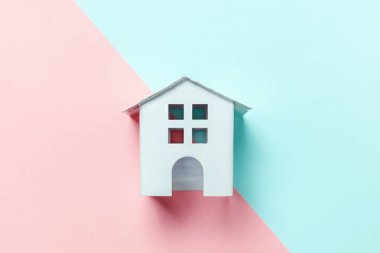 Sadece tasarım mavi, pembe pastel renkli trendy geometrik arka plan izole bir minyatür beyaz oyuncak ev. Mortgage Emlak sigorta rüya ev concept. Düz yatıyordu üstten görünüm kopya alanı