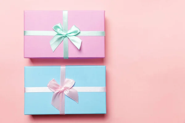 Christmas New Year birthday valentine celebration present romantic concept. Small gift box wrapped pink and blue paper isolated on pink pastel colorful trendy background. Flat lay top view copy space