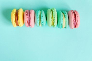 Tatlı badem rengi pembe mavi sarı badem kurabiyesi ya da modayı takip eden mavi pastada izole edilmiş badem kurabiyesi. Fransız kurabiyesi. Asgari gıda fırını konsepti. Düz görünüm kopyalama alanı