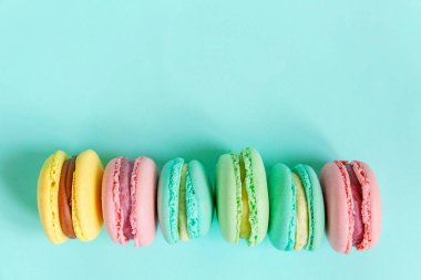 Tatlı badem rengi pembe mavi sarı badem kurabiyesi ya da modayı takip eden mavi pastada izole edilmiş badem kurabiyesi. Fransız kurabiyesi. Asgari gıda fırını konsepti. Düz görünüm kopyalama alanı