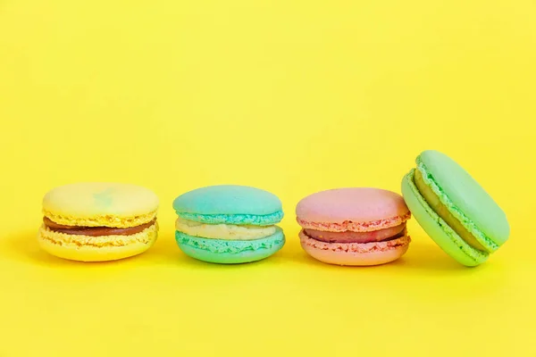 Sweet almond colorful unicorn pink blue yellow green macaron or macaroon dessert cake isolated on trendy yellow modern fashion background. French sweet cookie. Minimal food bakery concept. Copy space