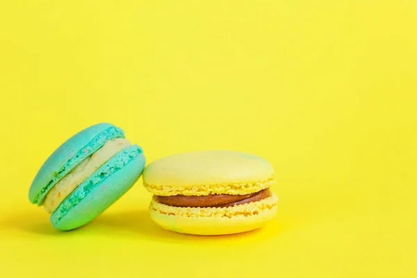 Sweet almond colorful unicorn blue yellow macaron or macaroon dessert cake isolated on trendy yellow modern fashion background. French sweet cookie. Minimal food bakery concept. Copy space