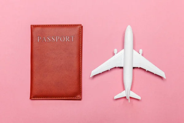 Minimal simple flat lay travel adventure trip concept with plane and passport on pink pastel trendy modern background
