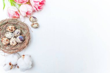 Paskalya yumurtaları yuvadan pamuk ve pembe taze tulip buket rustik Beyaz ahşap zemin üzerinde