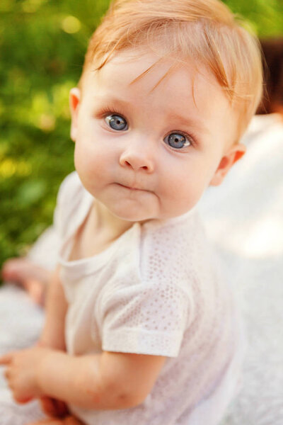 Sweet happy little baby girl sitting on grass in park, garden, meadow