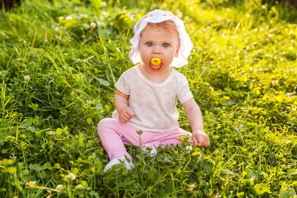 Dolce bambina felice seduta sull'erba nel parco, giardino, prato — Foto Stock